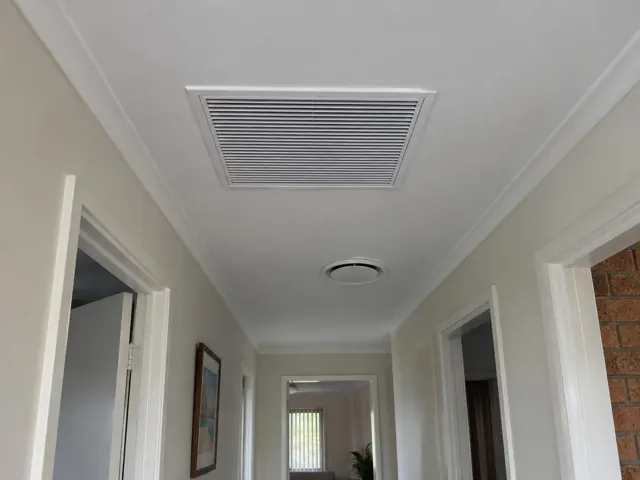 Hallway ceiling with a large return-air grille and round ceiling outlet in a painted home interior in Biggera Waters